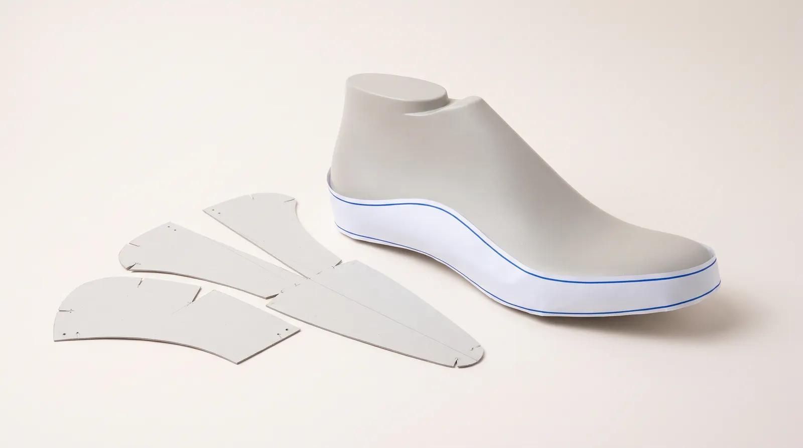 A shoe last with a paper base pattern wrapped around its side, next to cardboard pattern pieces.